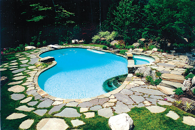 Natural stone pathway leading to a pool surrounded by greenery